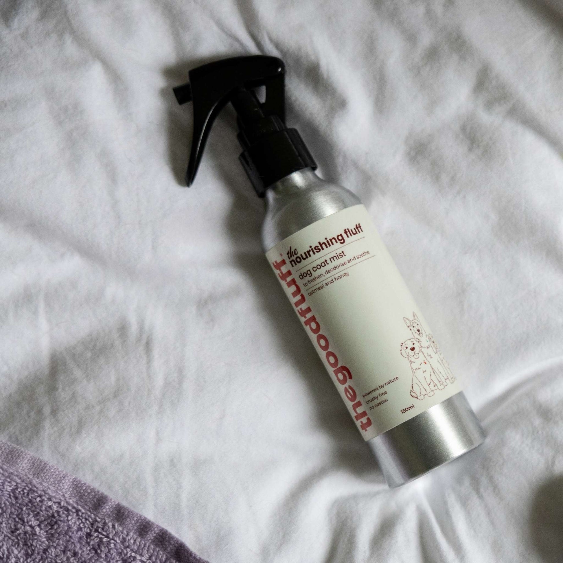 Aluminium spray bottle of the Good Fluff coat mist laid on a white duvet