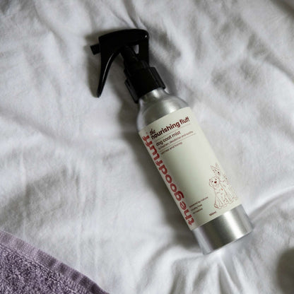 Aluminium spray bottle of the Good Fluff coat mist laid on a white duvet