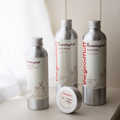 Set of 'the nourishing fluff' natural pet care products with aluminium screw caps on a light coloured shelf with a neutral background.